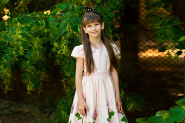 Naklejka premium Portrait of beautiful little girl in elegant dress in green summer field