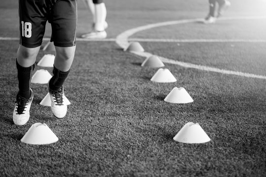black and white picture of soccer player Jogging and jump between cone markers on artificial turf for soccer training
