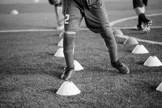 black and white picture of soccer player Jogging and jump between cone markers on artificial turf for soccer training