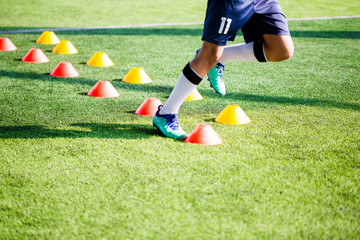 Soccer player Jogging and jump between cone markers on green artificial turf for soccer training