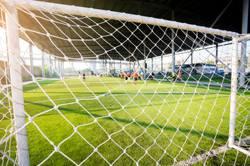White mesh goal with blurry young boy soccer players sitting with coach