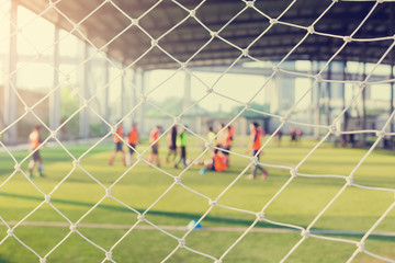 White mesh goal with blurry young boy soccer players sitting with coach