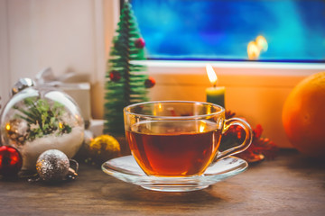 festive tea party. a cup of tea and a teapot. on the background of New Year and Christmas decorations. near the window with a blue, cold, winter background.