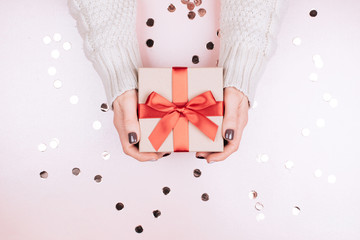 Gift box with bow in woman's hands. Living Coral - Color of the Year 2019.