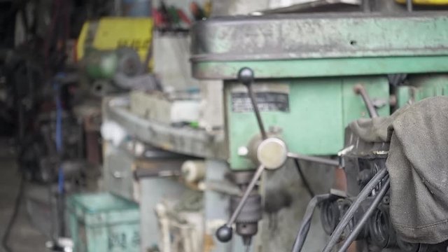 Drilling machine storing inside of old dirty garage. Slowly shift focus handheld slow-motion shot, 29.97fps.