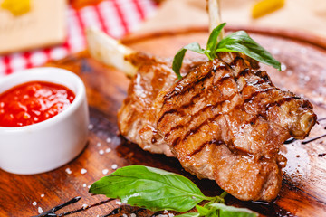 Rack of lamb fried with aromatic olive oil, herbs and spices on wooden board. Close up