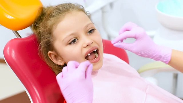 the child is a sweet girl without front milk teeth in the dental chair. Children's dentist