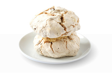 Cake meringue with hazelnuts and dates on plate against white background
