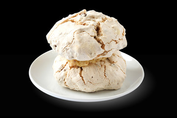 Plate with cake meringue with hazelnuts and dates isolated on black background