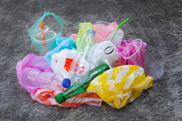 Colorful plastic waste, bags, cups, bottles, straws on cement