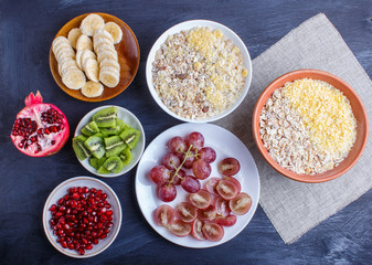 A set of plates with muesli, grapes, kiwi, pomegranate, banana on a black background.