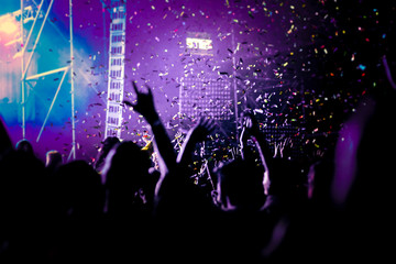 Fototapeta na wymiar cheering crowd with raised hands and falling confetti at concert - music festival