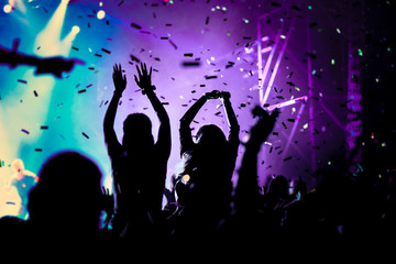 Fototapeta na wymiar cheering crowd with raised hands and falling confetti at concert - music festival