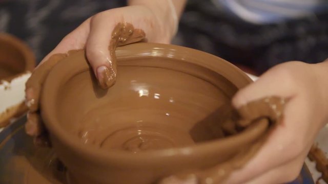 Close-up hands of a male potter in apron molds bowl from clay. Hobby,lifestyle concept.