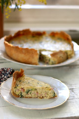 Slice of homemade quiche filled with cheese, ham and leek. Selective focus.