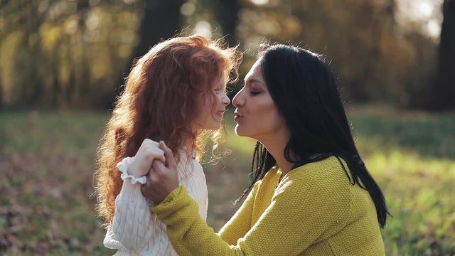Mom and daughter playing in autumn park, They eating, laughing and smiling. slow-motion