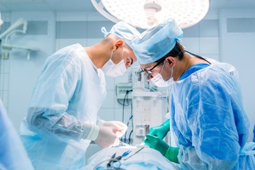Neurosurgeon with an assistant doing surgery in intensive care