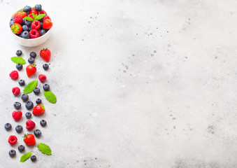 Fresh raw organic berries in white ceramic bowl plate on kitchen table background. Space for text. Top view. Strawberry, Raspberry, Blueberry and Mint leaf