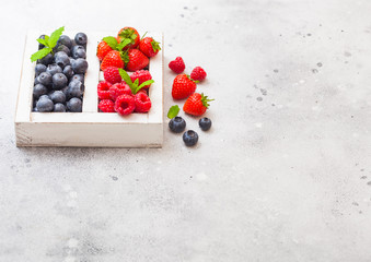 Fresh raw organic berries in white vintage wooden box on kitchen table background. Space for text. Top view. Strawberry, Raspberry, Blueberry and Mint leaf