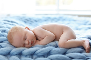 Adorable newborn baby lying on knitted blanket indoors