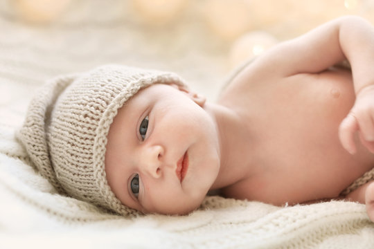 Adorable newborn baby in hat lying on bed