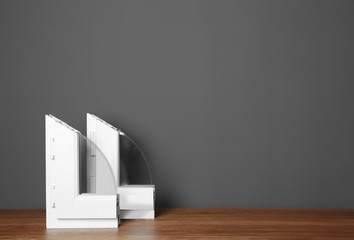 Samples of modern window profiles on table against gray wall, space for text. Installation service