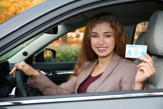 Happy woman holding driving license in car