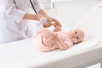 Obraz na płótnie Canvas Children's doctor examining baby with stethoscope in hospital