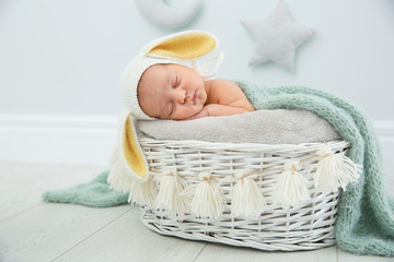 Obraz premium Adorable newborn child wearing bunny ears hat in baby nest indoors