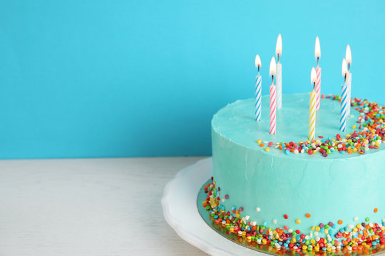 Fresh delicious birthday cake with candles on table against color background. Space for text