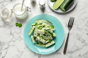 Plate with delicious cucumber salad served on marble table, top view