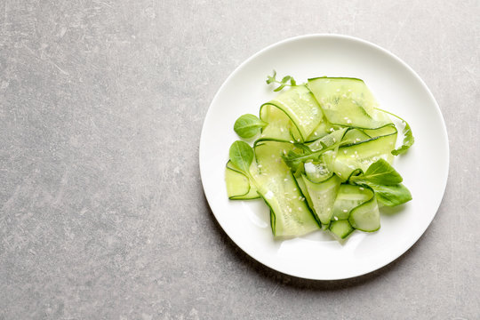 Plate with delicious cucumber salad on grey background, top view. Space for text