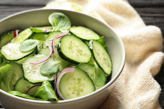 Fototapeta Delicious cucumber salad with onion and spinach in bowl on table, closeup