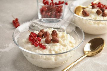Creamy rice pudding with red currant and hazelnuts in bowls served on grey table