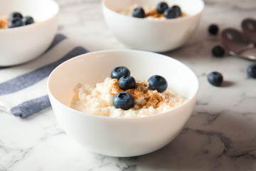 Creamy rice pudding with cinnamon and blueberries in bowl on marble table