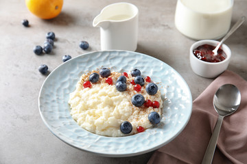 Creamy rice pudding with red currant and blueberries in bowl served on table