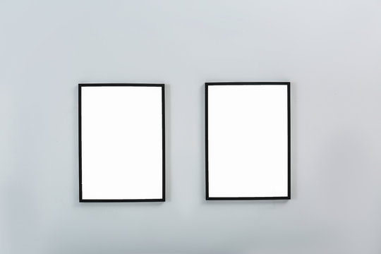 Frames with empty canvases on wall in modern art gallery. Mockup for design