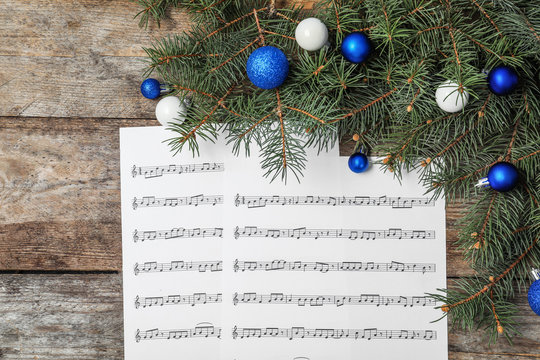 Composition with music sheets and Christmas decor on wooden background, top view