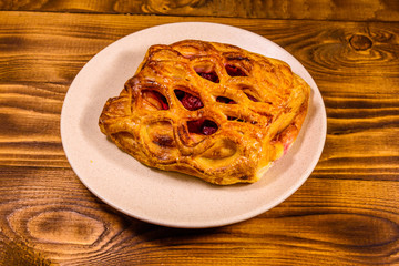 Ceramic plate with fresh cherry strudel on wooden table
