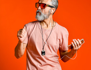 Enjoying the sound of music. Studio portrait of handsome senior man with gray beard and headphones. - Powered by Adobe