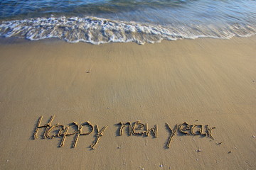 Happy new year write on sand the beach.