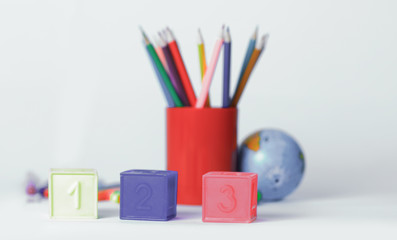 cubes with numbers on blurred school supplies background