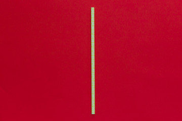 Yellow paper straw, isolated on red background. 