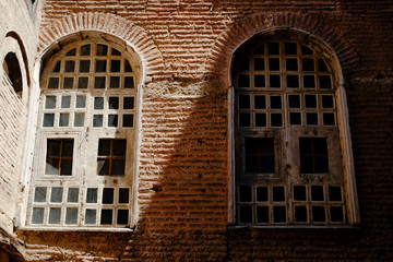 Fototapeta na wymiar Two windows in shade and light on tile brick wall