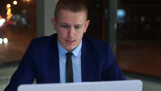 Tired young businessman working overtime on a laptop.