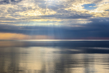 Fototapeta premium Sun rays and clouds over lake
