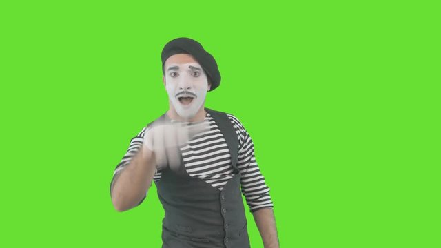 Happy mime showing thumbs up. Cheerful behavior and broad smile of a male actor during the pantomime show. Isolated on green background.