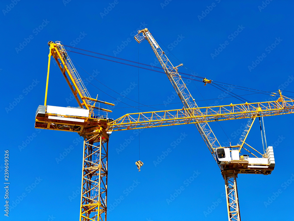 Wall mural two tower crane construction on blue sky background