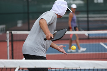 A senior athlete serves during a tournament pickleball match.