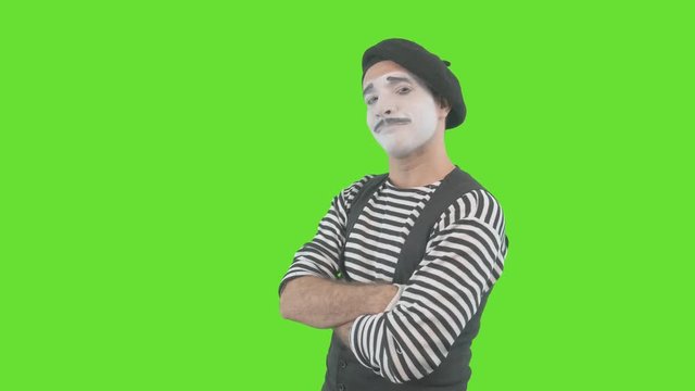 Happy mime showing thumbs up. Cheerful behavior and broad smile of a male actor during the pantomime show. Isolated on green background.